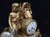 a gold clock with a statue of a boy and a sheep