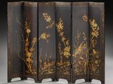 un paravent noir et doré orné de fleurs et d'oiseaux