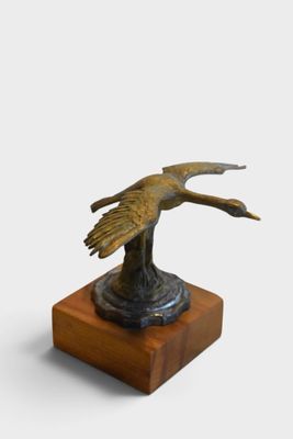 bronze statue of a bird on a wooden base on a white background