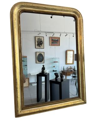 a gold framed mirror in the middle of a room