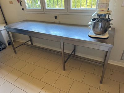 une grande table en métal sur laquelle est posé un mixeur, dans une cuisine