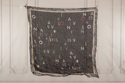 un morceau de tissu noir sur lequel sont inscrites des lettres, suspendu à une corde à linge