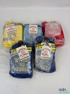 Plusieurs t-shirts de différentes couleurs sont emballés dans des sacs en plastique, posés sur une surface blanche.