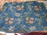 a blue dress with pink flowers on it laying on a bed