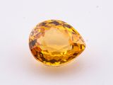 a yellow sapphire stone on a white surface