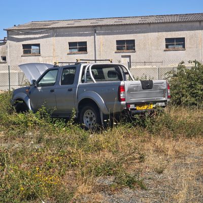 a truck that is parked in the grass by a building