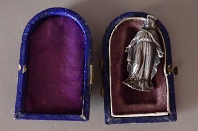 an image of a silver statue of the virgin mary in a purple box