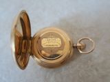 a gold pocket watch with a chain on a white surface