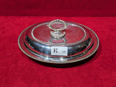une assiette en argent ornée d'un cerf sur un fond rouge