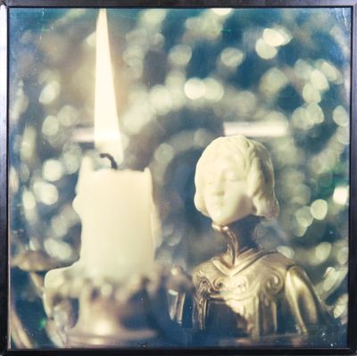 une photo représentant une bougie et une statue devant un sapin de Noël