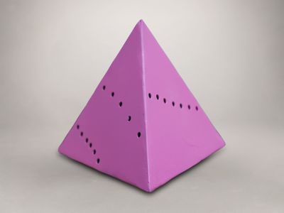 un gros plan d'un objet rose en forme de pyramide posé sur une surface blanche