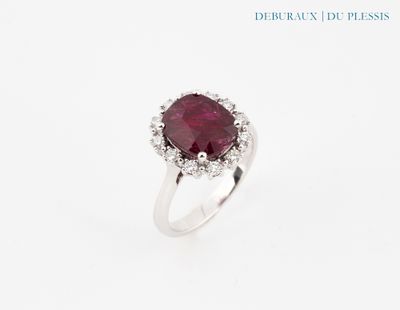 gros plan d'une bague avec une pierre rouge entourée de diamants