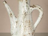 une théière blanche posée sur une table, sur fond marron