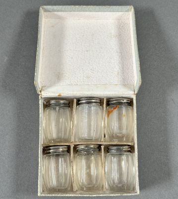 six bocaux en verre dans une boîte blanche posée sur une surface grise