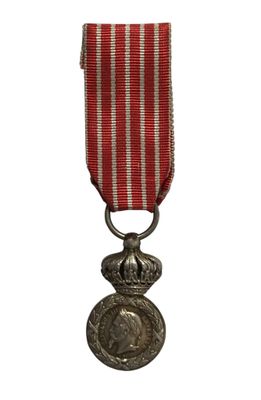 une vieille médaille ornée d'un ruban rouge et d'une médaille en argent