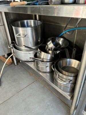 many pots and pans on the shelf in the kitchen