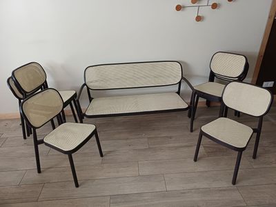 plusieurs chaises et une table dans une pièce où est accrochée une horloge au mur