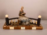 une statue représentant une femme assise sur un banc