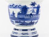 un vase bleu et blanc sur lequel est représentée une maison