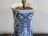 un vase bleu et blanc sur lequel est posée une lampe