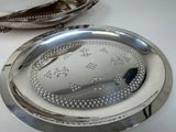 two silver trays on a white table with a spoon and spoon rest