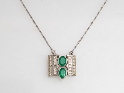 un pendentif composé d'une pierre verte et d'un diamant, monté sur une chaîne en argent
