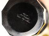 a close up of a black vase with writing on it