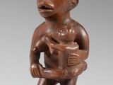 une statue en bois représentant un homme tenant un bébé dans ses bras