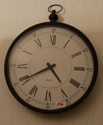 une horloge en noir et blanc accrochée au mur, avec des chiffres romains