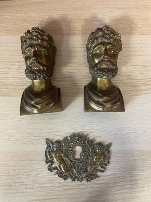 two antique brass busts of men on a wooden table