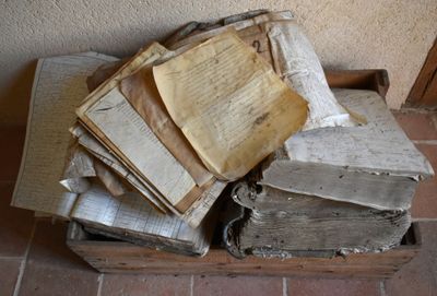 pile de vieux livres posés sur une boîte en bois sur un sol carrelé