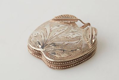 a small silver box with a leaf design on it