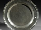 un vieux plat en argent posé sur une table blanche