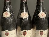 six bottles of red wine are lined up on a shelf