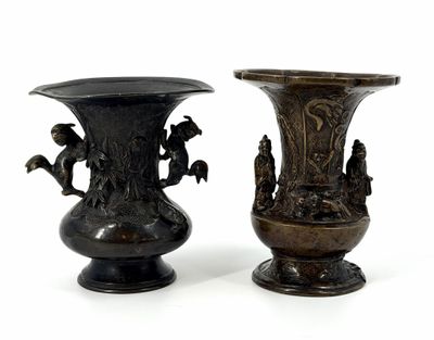 two bronze vases sitting side by side on a white surface
