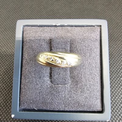 une alliance en or jaune sertie de diamants, présentée dans un coffret cadeau posé sur une table
