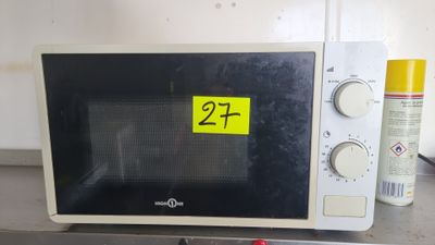 un micro-ondes sur lequel est collé un autocollant jaune, posé sur un plan de travail