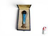 a small blue glass object in a box on a white surface