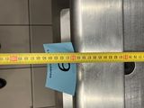 a measuring tape that is on the side of a stainless steel urinal