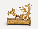 une figurine en or représentant une calèche tirée par des chevaux, avec un homme à bord