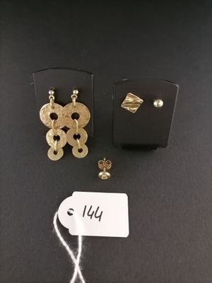 two pairs of gold earrings and a tag on a black surface