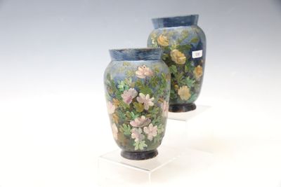 two vases with flowers painted on them sitting on a stand