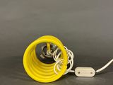a close up of a yellow lamp on a table with a white cord