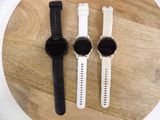 Trois montres sont posées sur une table ronde en bois, avec un bracelet blanc.