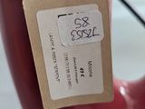 a red vase with a tag on it sitting on a table
