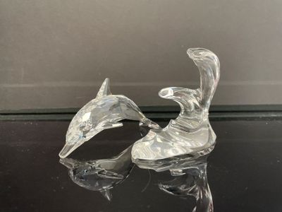 une paire de figurines de cygnes en verre transparent posées sur une table noire