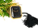 a black and gold watch with a tassel on a table