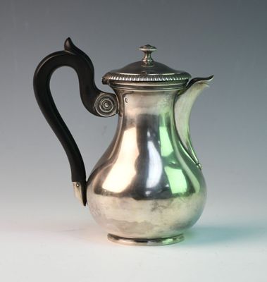 a silver coffee pot with a black handle on a table