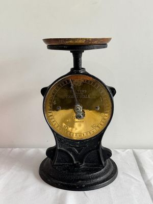 une vieille balance noire et dorée posée sur une table blanche