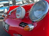 une voiture de sport rouge garée devant une enseigne rétro